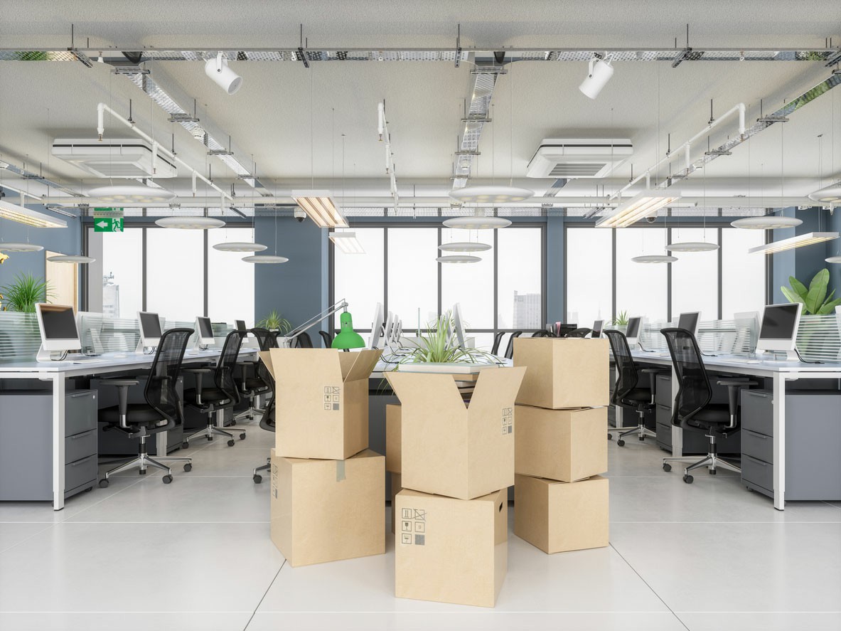 Engage Professional Office Relocation Experts An office space filled with stacked boxes and chairs, indicating preparation for relocation by professional movers;